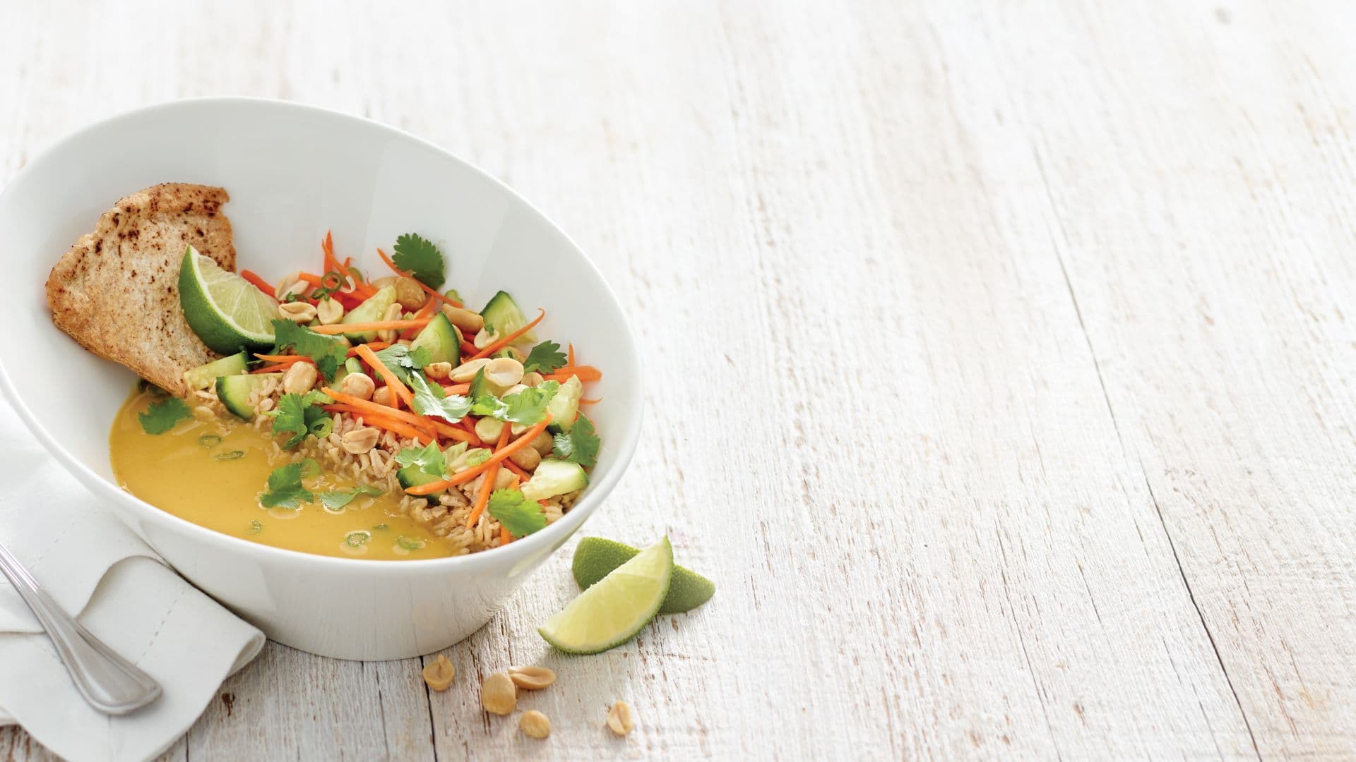 Colorful vegetable curry bowl with lime and bread.
