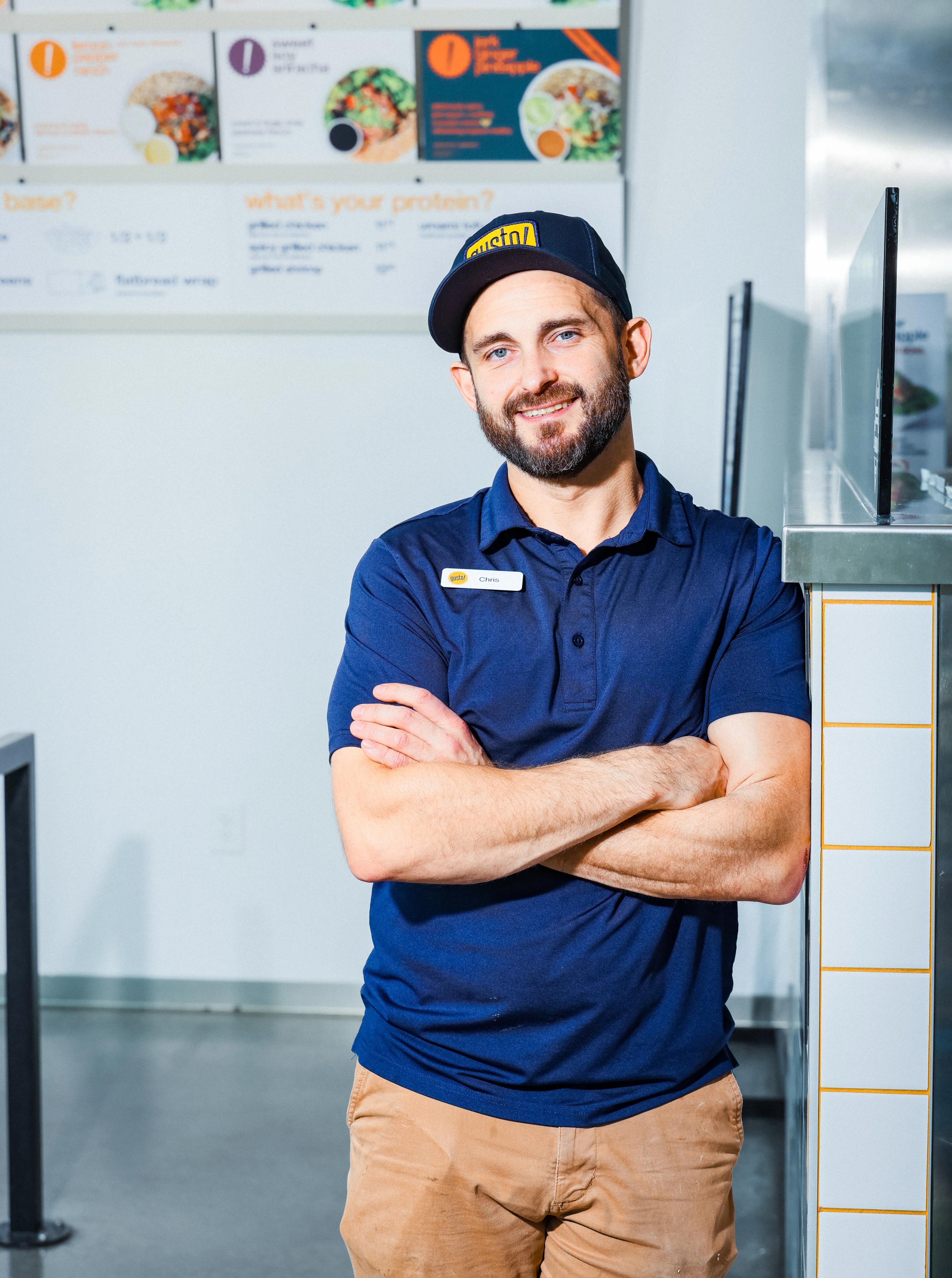 Manager of gusto! restaurant in uniform leaning against wall smiling