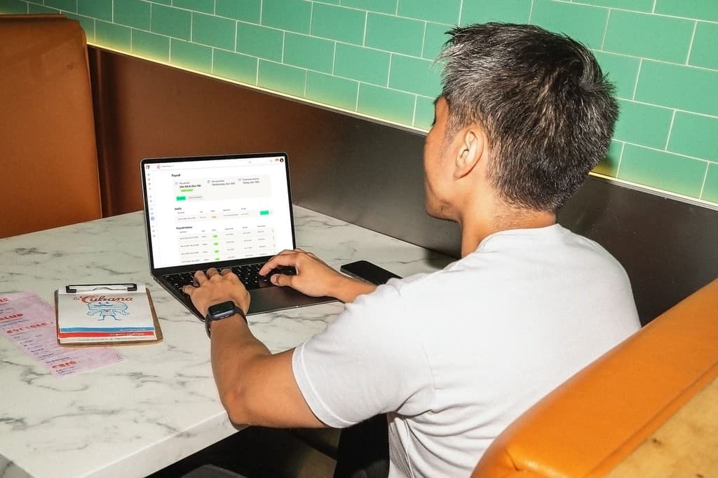 Restaurant manager running payroll on a laptop with 7shifts