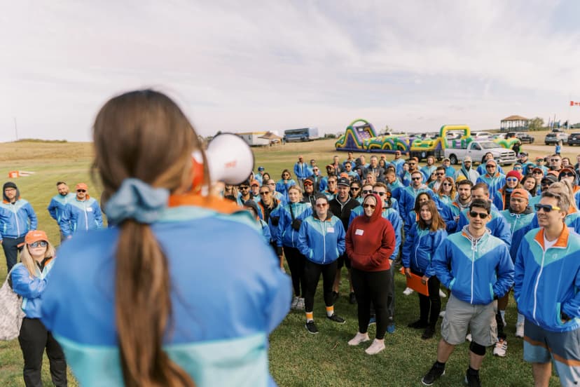 Outdoor team meeting with speaker and large group.