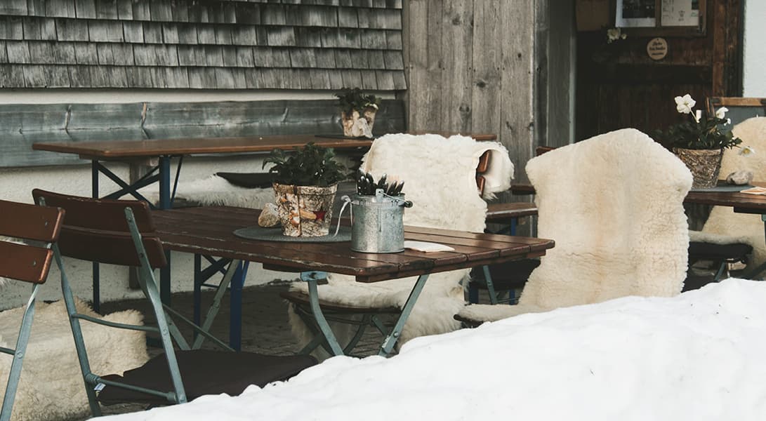 Cozy outdoor seating with fur-draped chairs in snow.