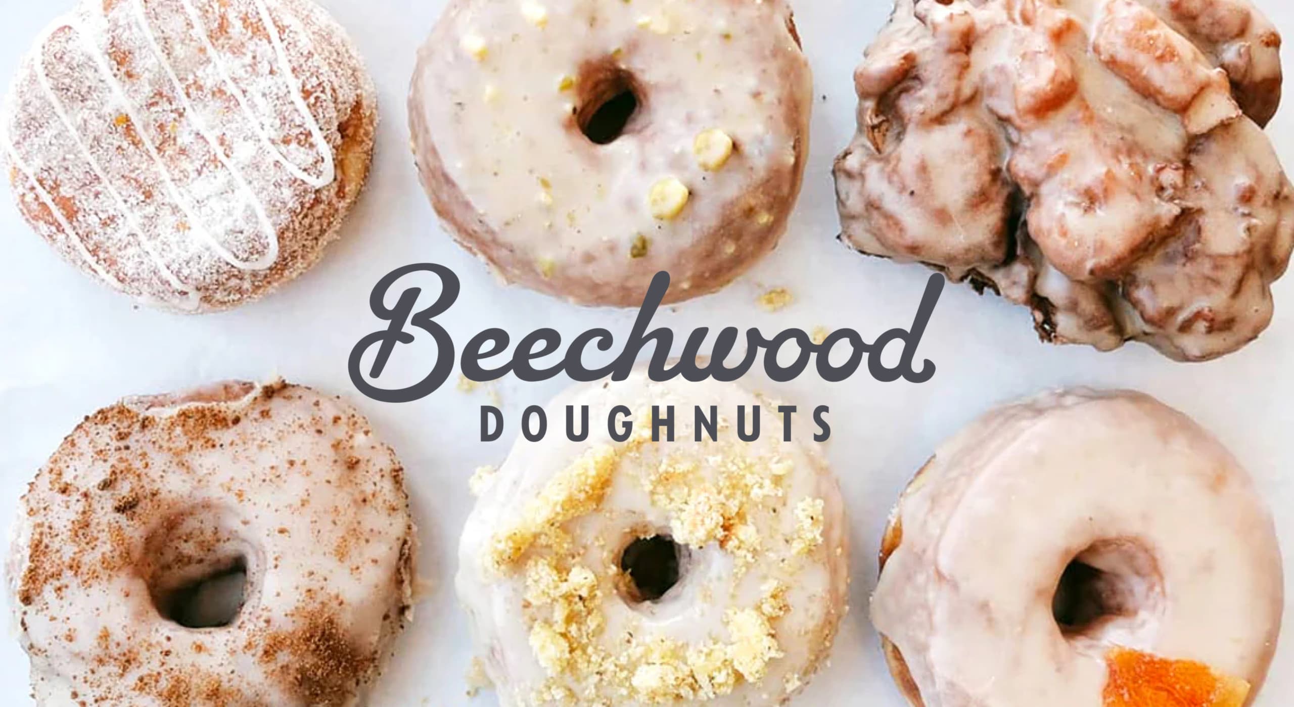 Image of donuts laid on table with 'Beechwood Doughnuts' logo on top
