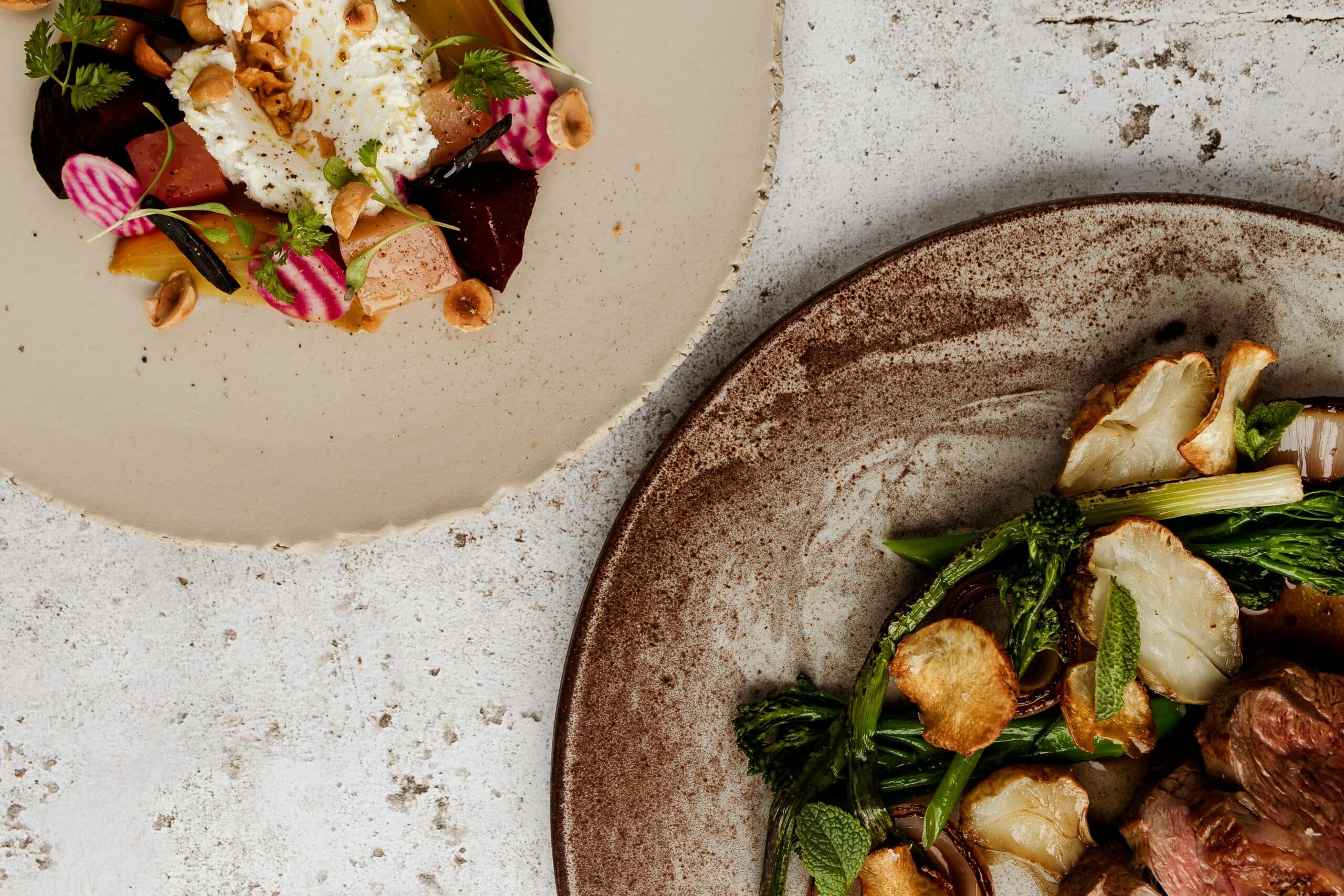 Gourmet dishes with vegetables and meats on rustic plates.
