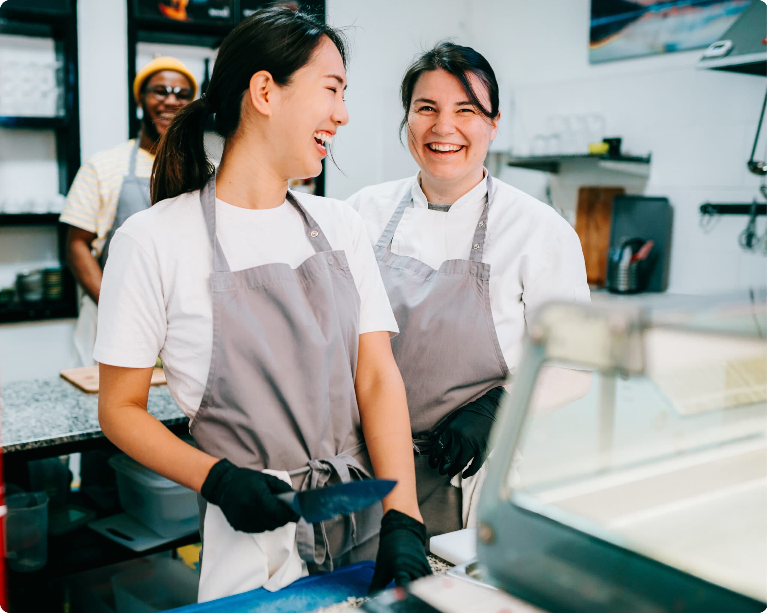 Two women laughing while cooking in restaurant kitchen