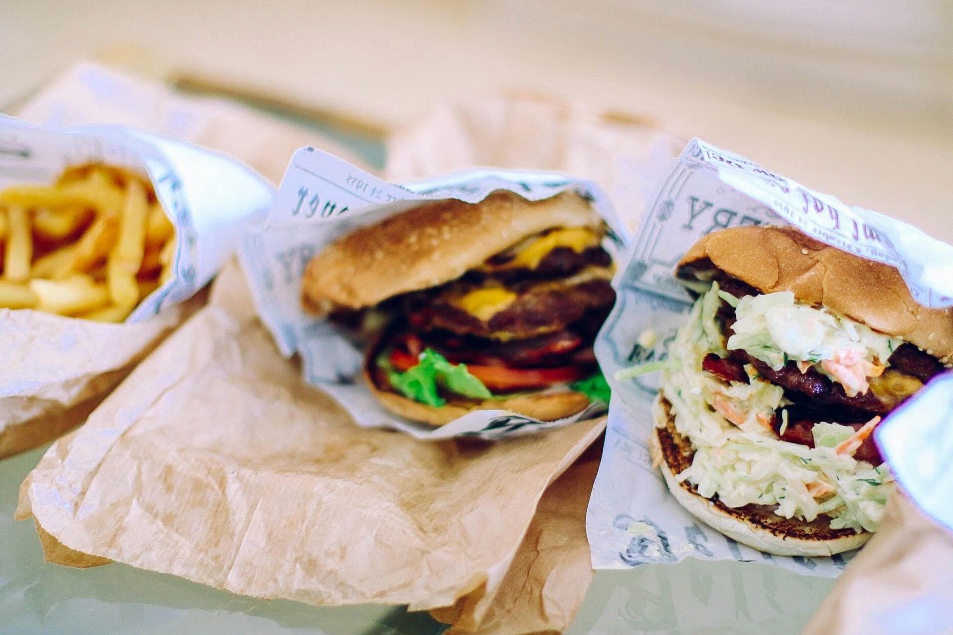 Cheeseburgers and fries wrapped in paper on table.