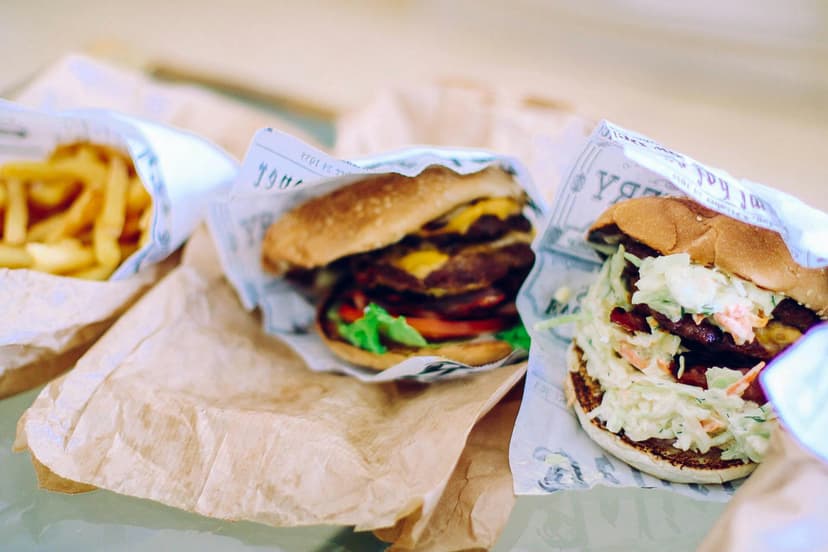 Cheeseburgers and fries wrapped in paper on table.