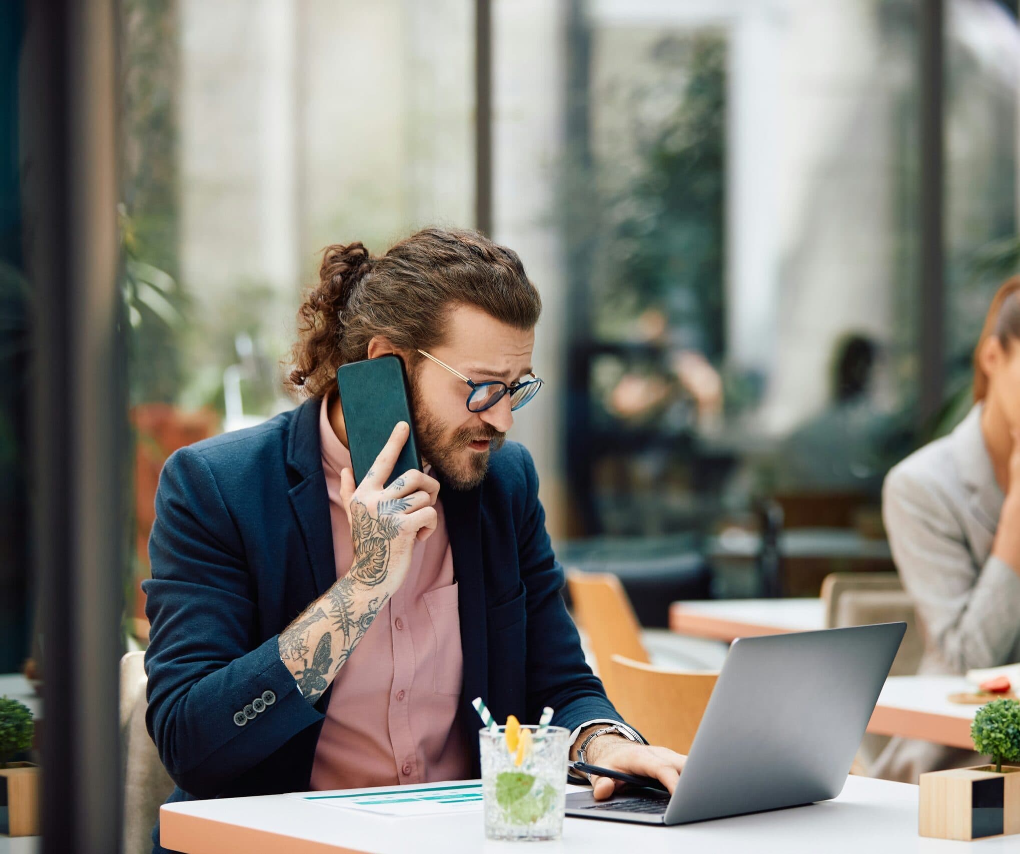 Photograph of restaurant manager using 7shifts on phone and laptop at a restaurant