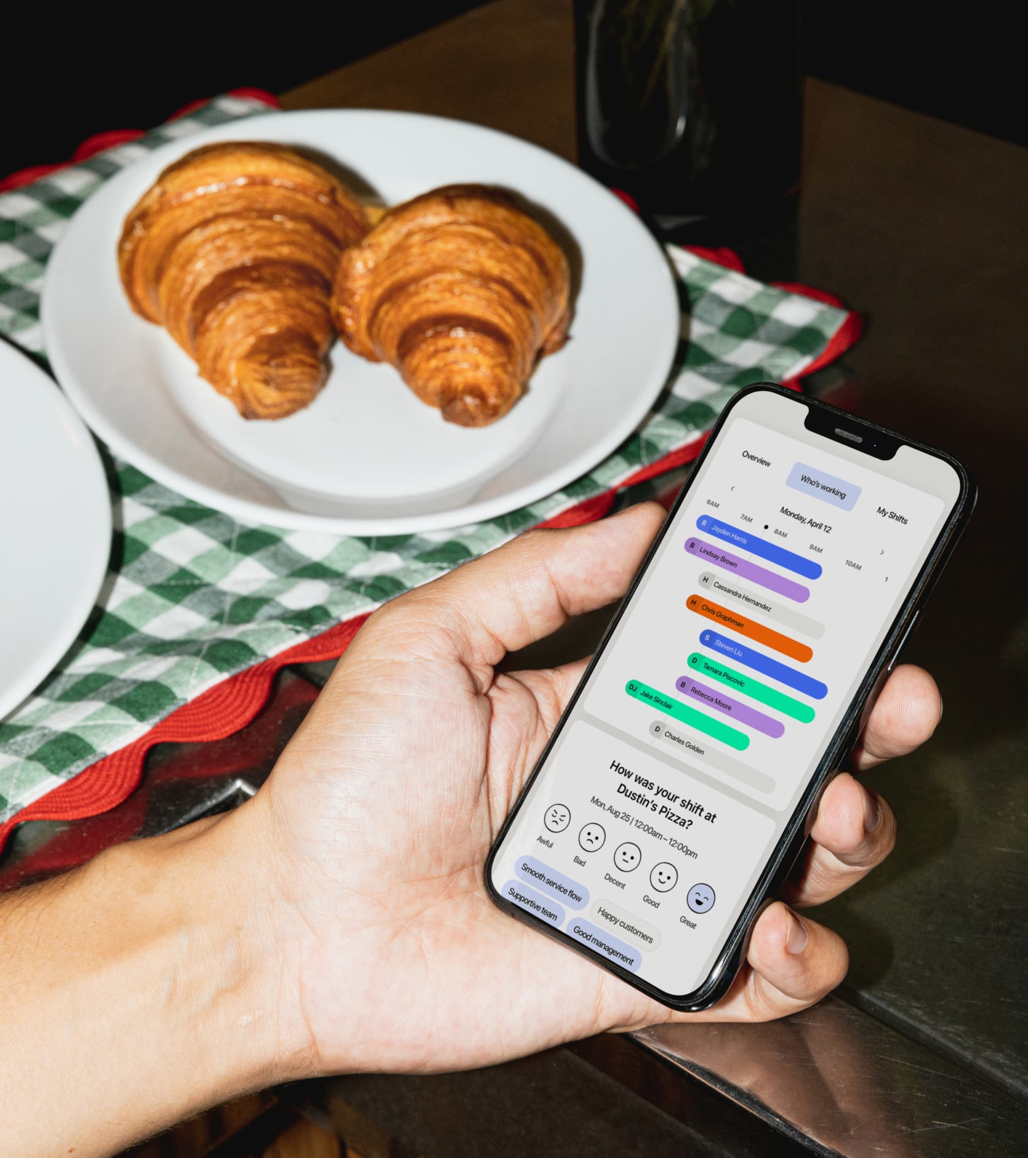 Person checks schedule app beside croissants on table.