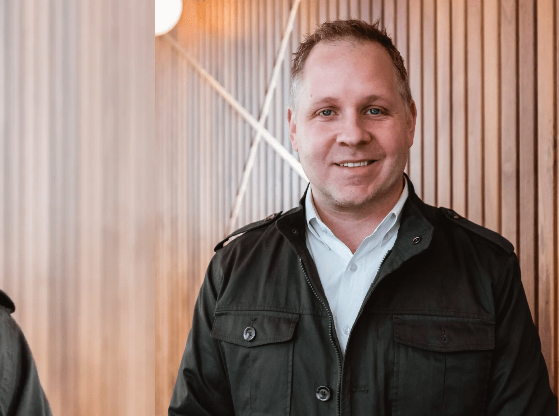 Smiling man in office setting, wooden background.