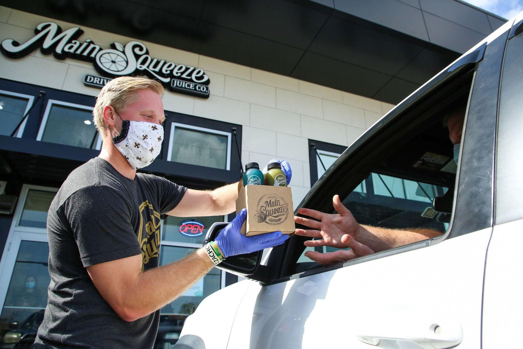 Masked worker hands drinks to driver at Main Squeeze.