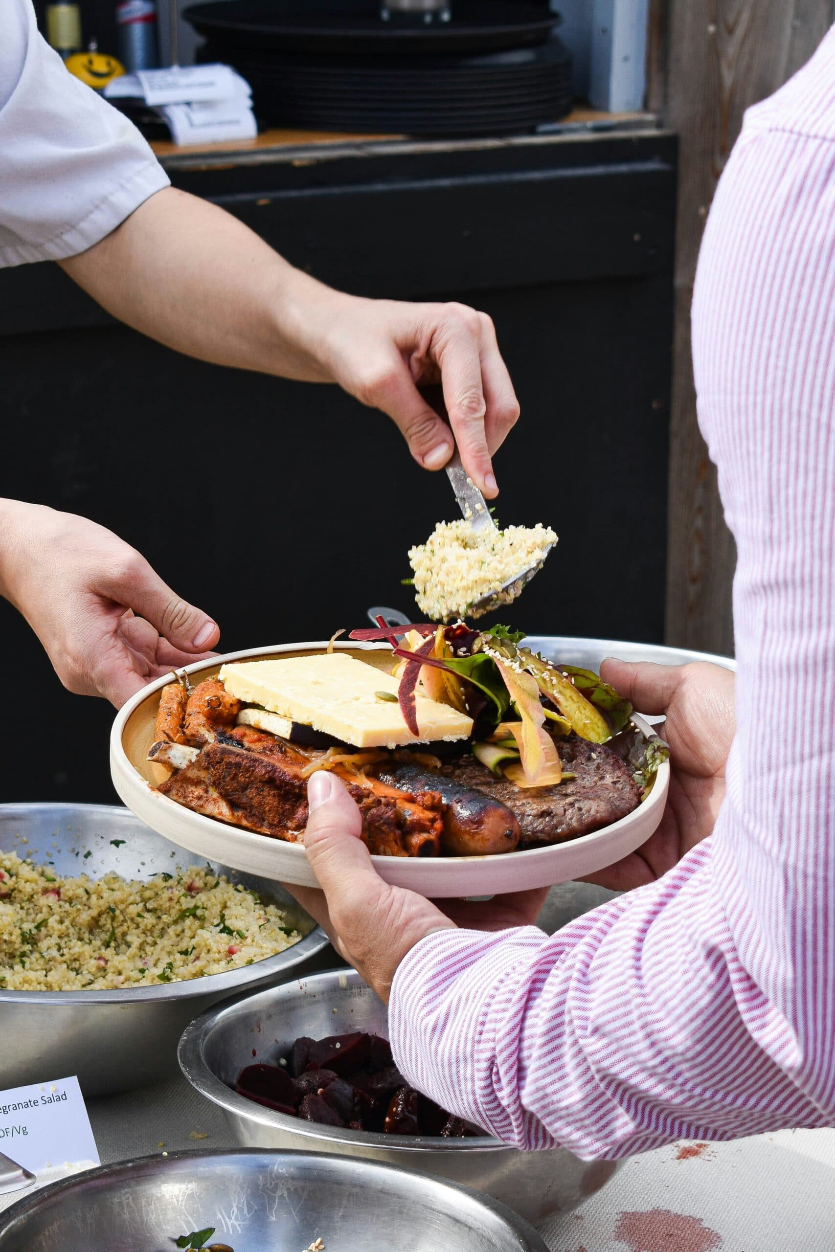 Person serving plate with salad and grains.