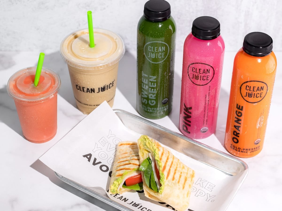 Assorted juices with wraps and smoothies on tray.