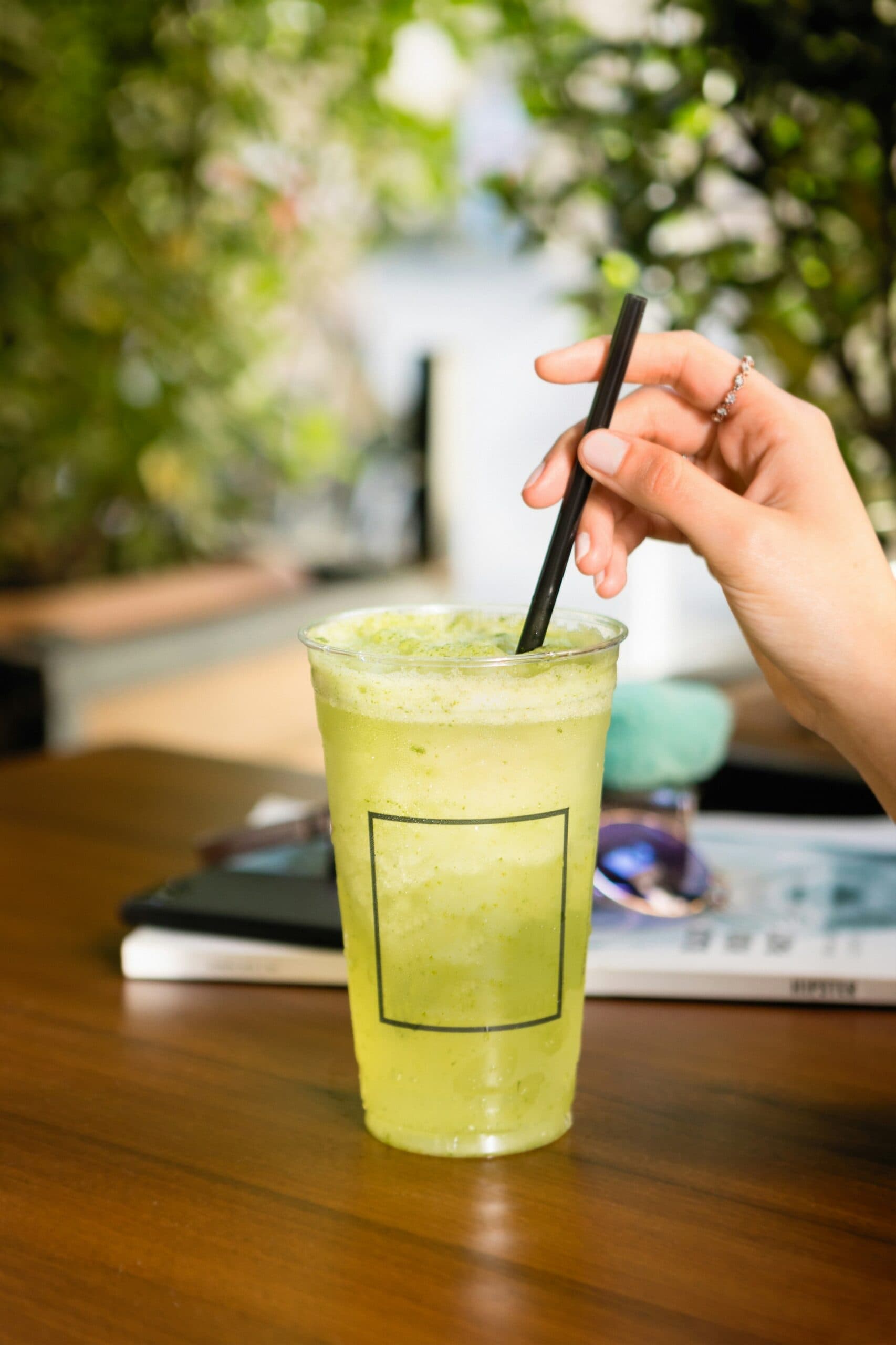 Person holding straw in frothy green drink