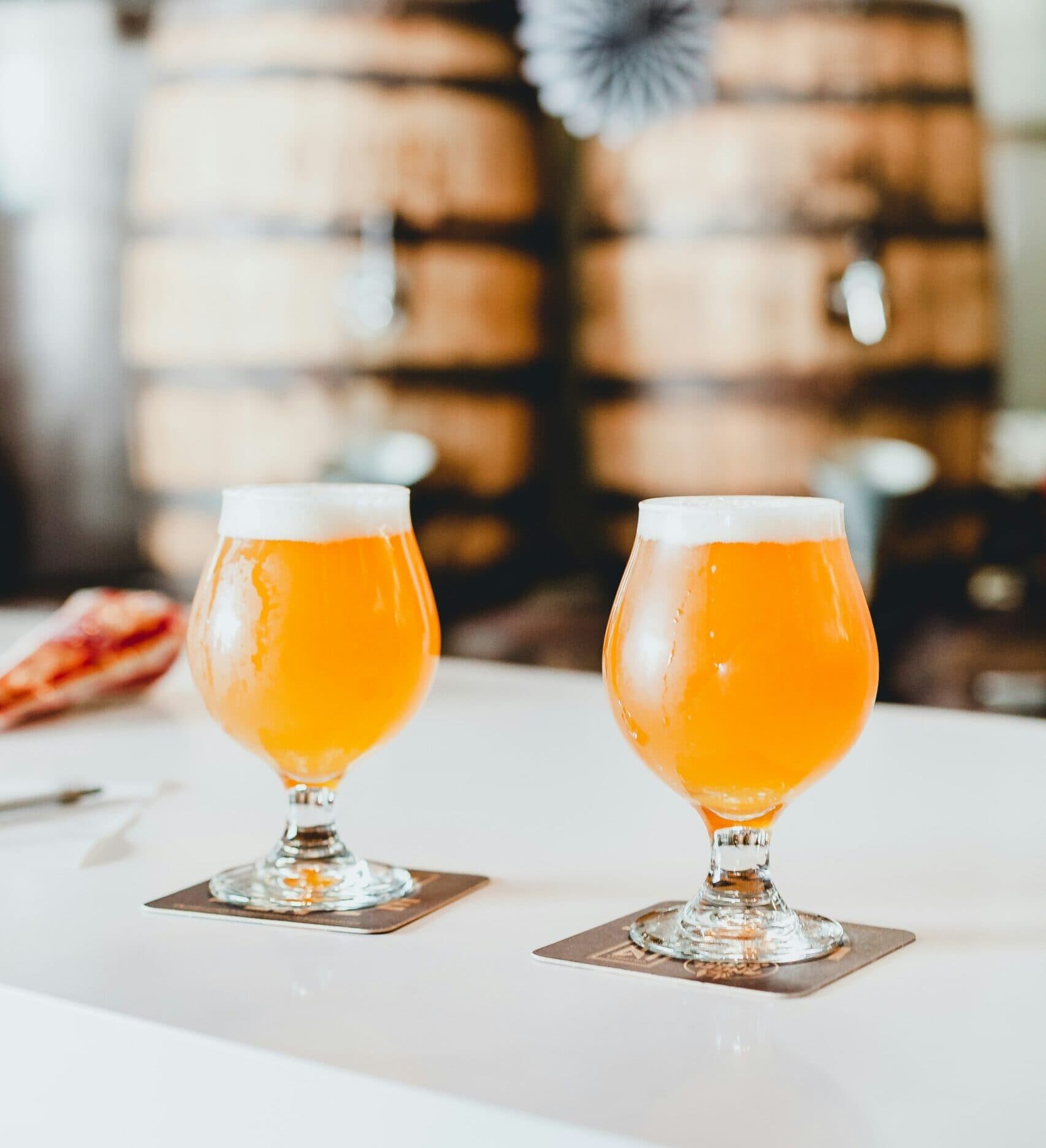 Two glasses of beer on a bar counter.