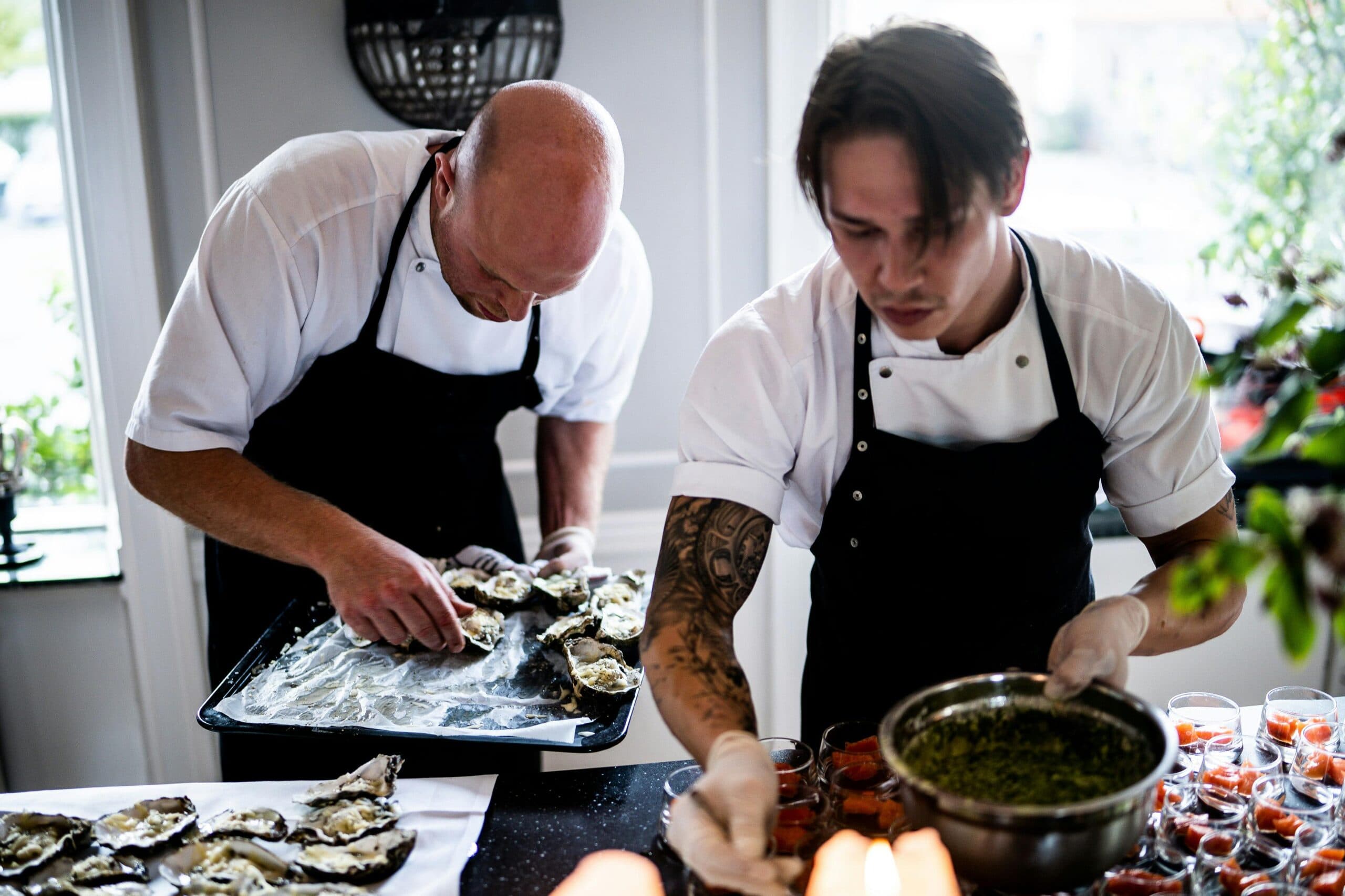Chefs preparing oysters in restaurant kitchen.