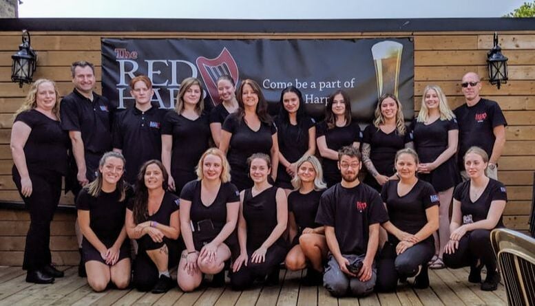 Group photo in front of bar sign.