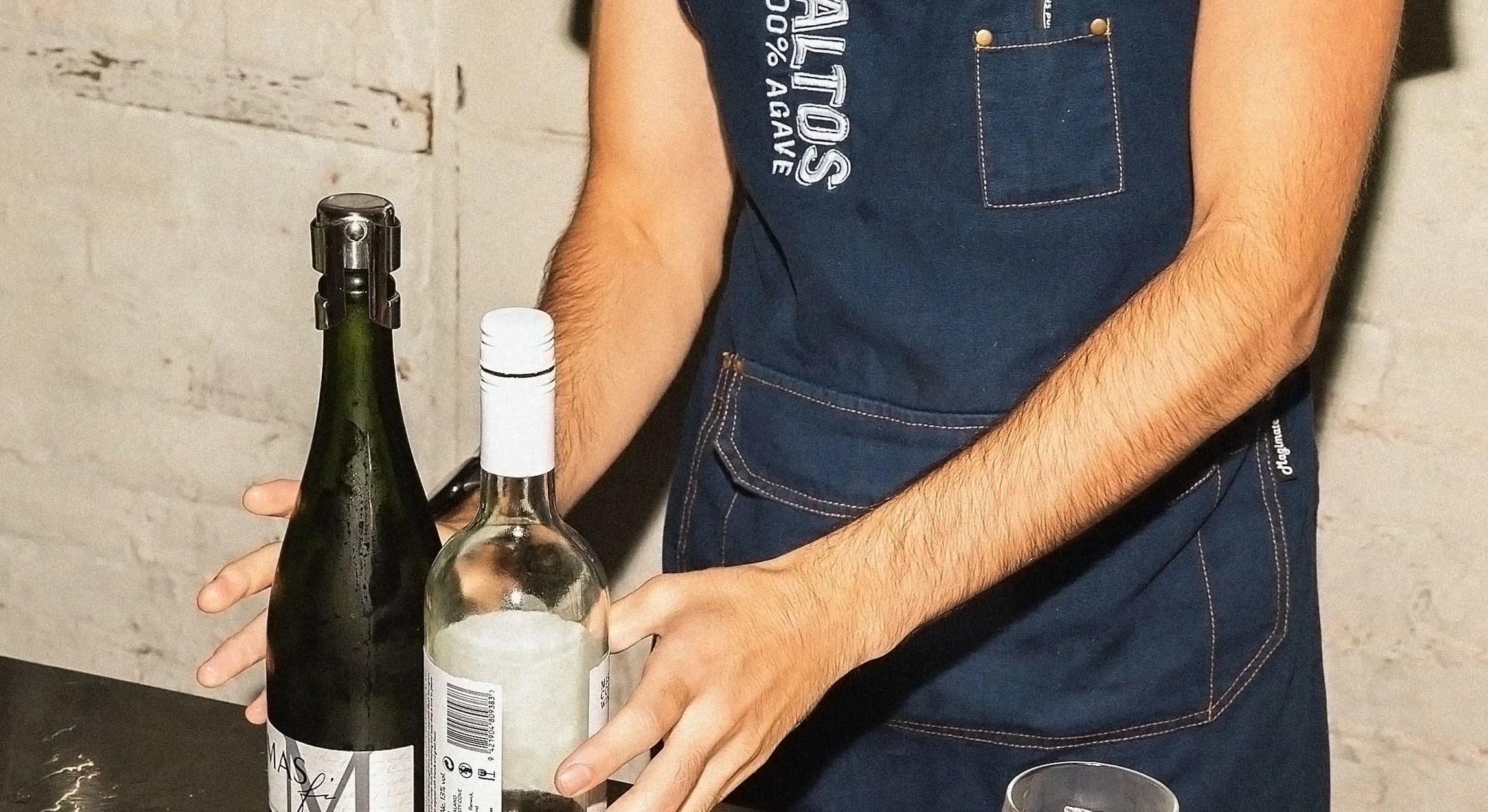 Person holding two bottles on counter.