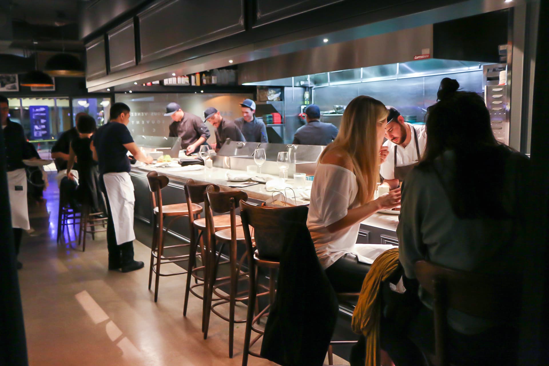 Chef preparing dishes in open kitchen restaurant.