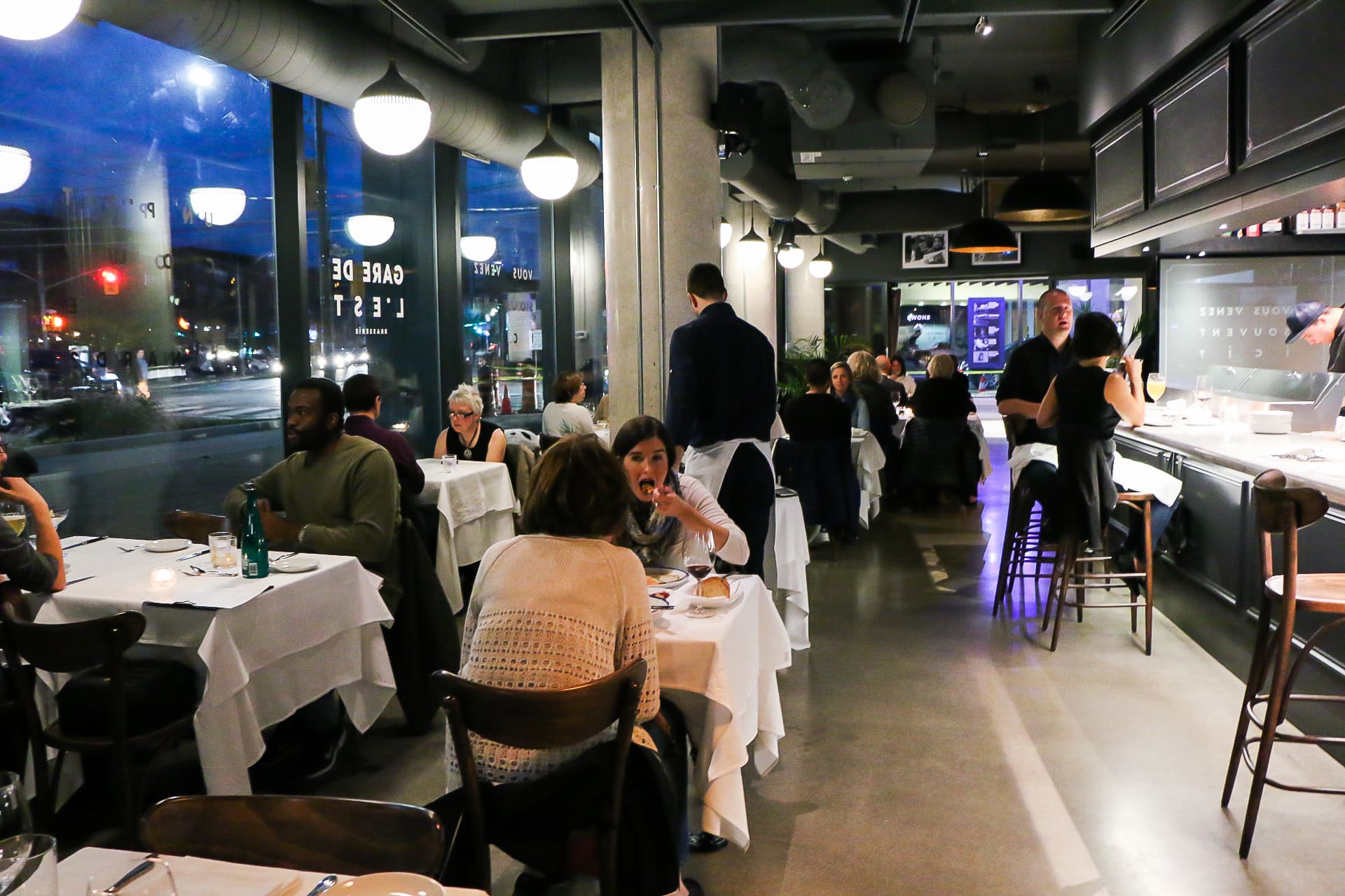 Busy restaurant interior with dining patrons at night.