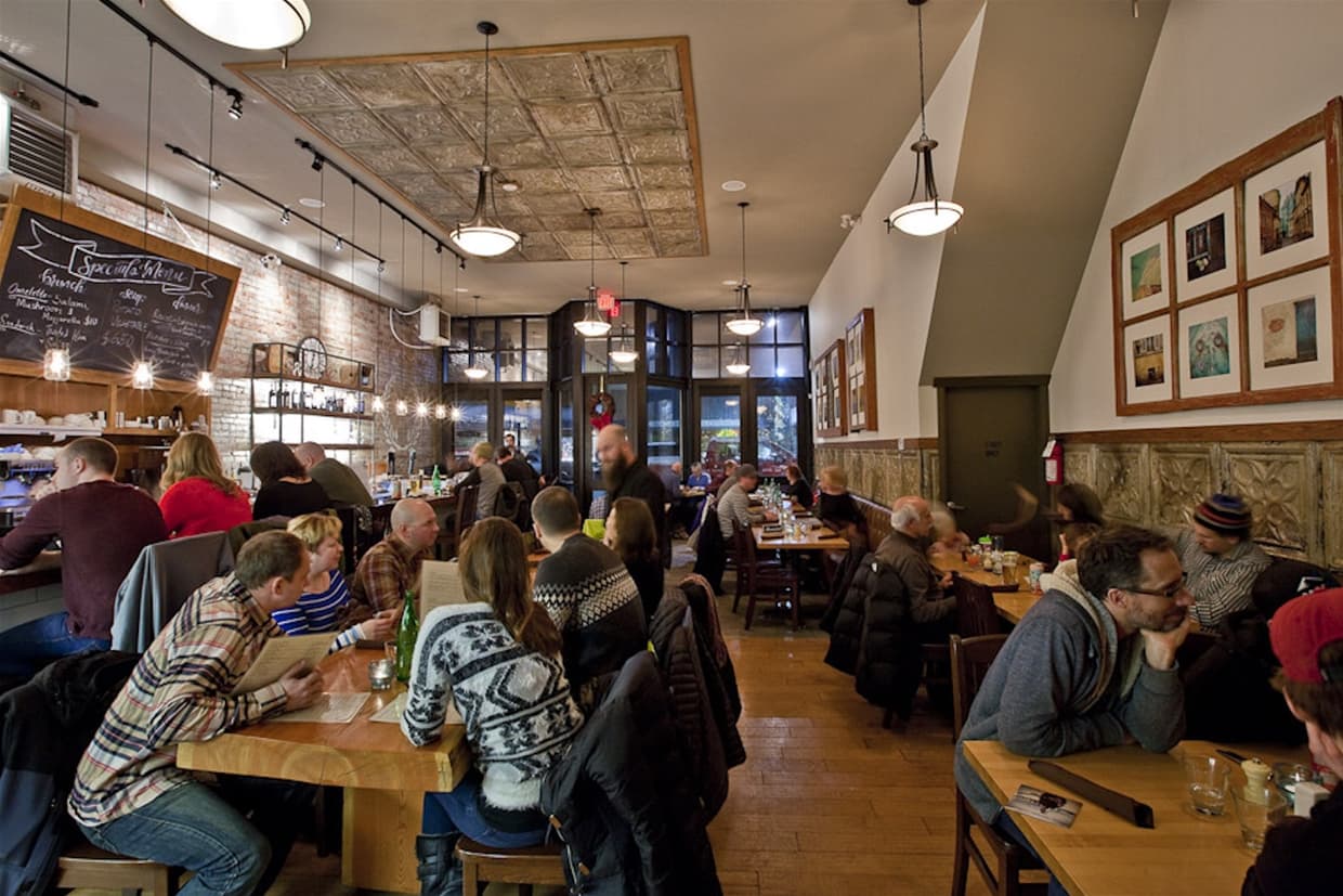 Cozy restaurant full of people dining and socializing.