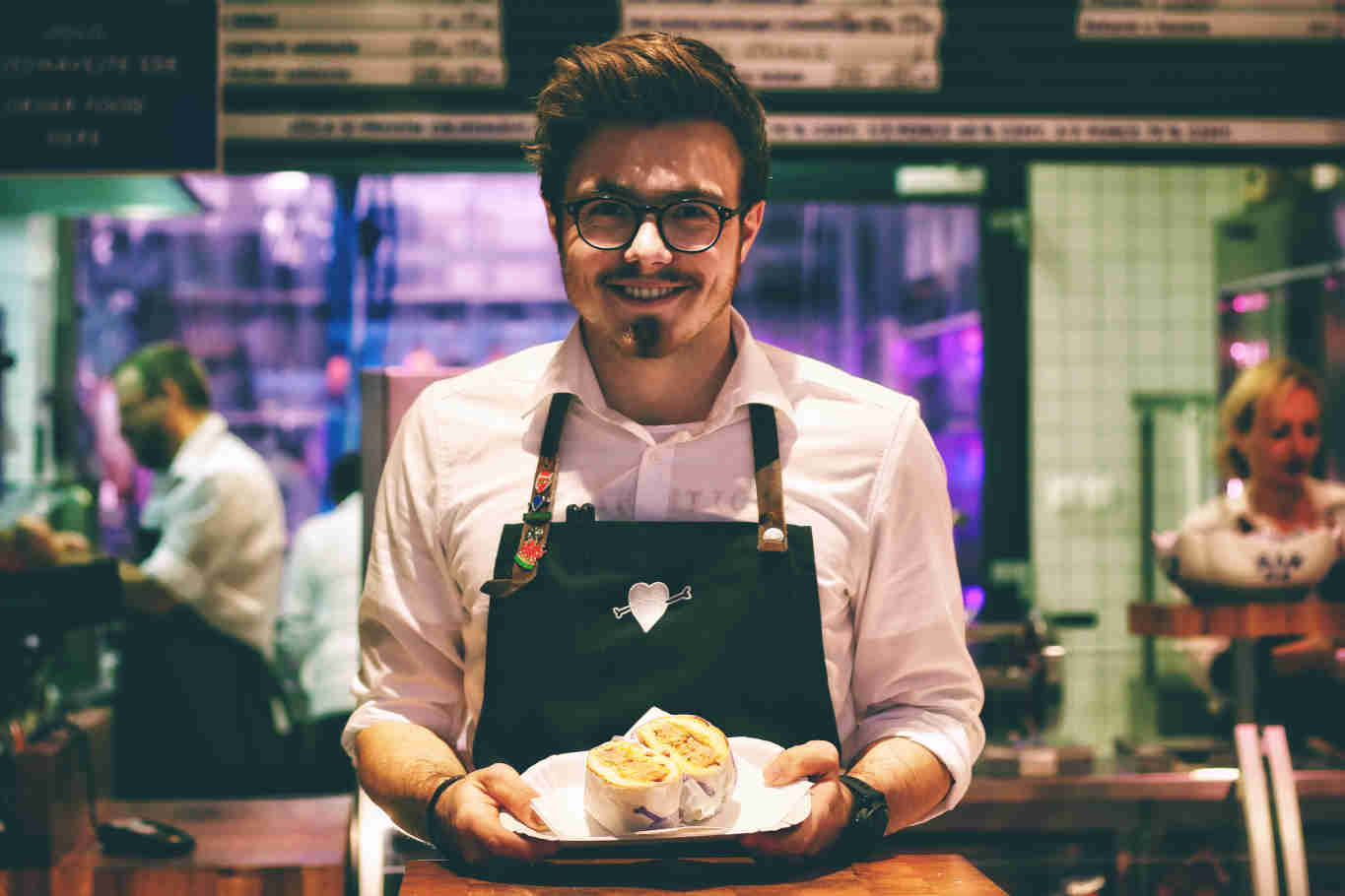 Smiling chef presenting sandwich on plate