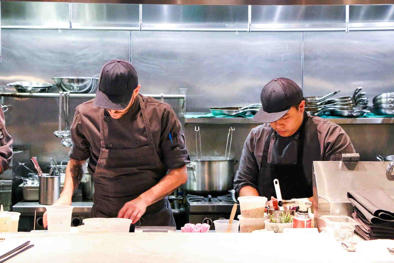 Chefs preparing food in a busy kitchen.