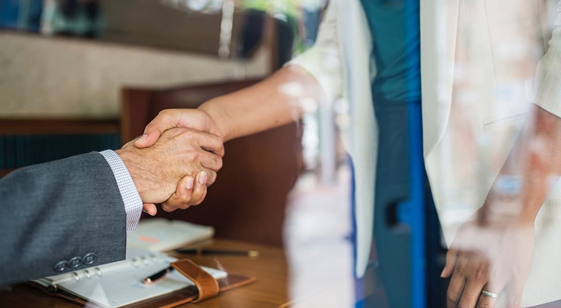 Two people shaking hands in an office.