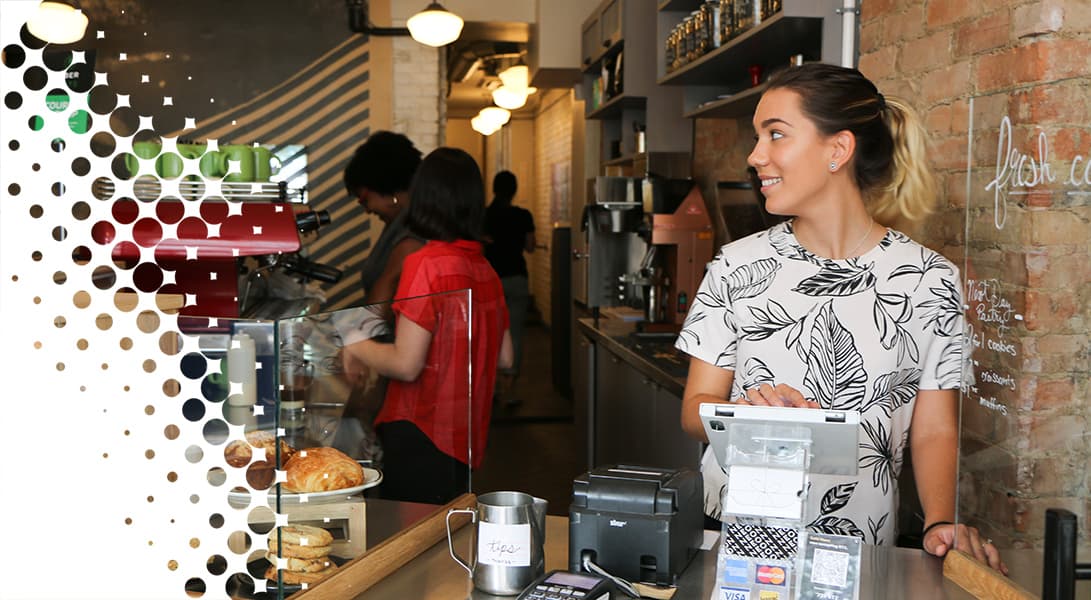 Friendly barista serving customers in cozy coffee shop.
