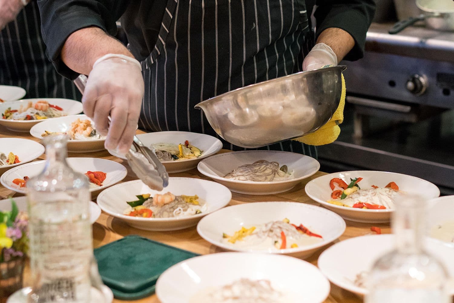 Chef preparing multiple seafood pasta dishes.