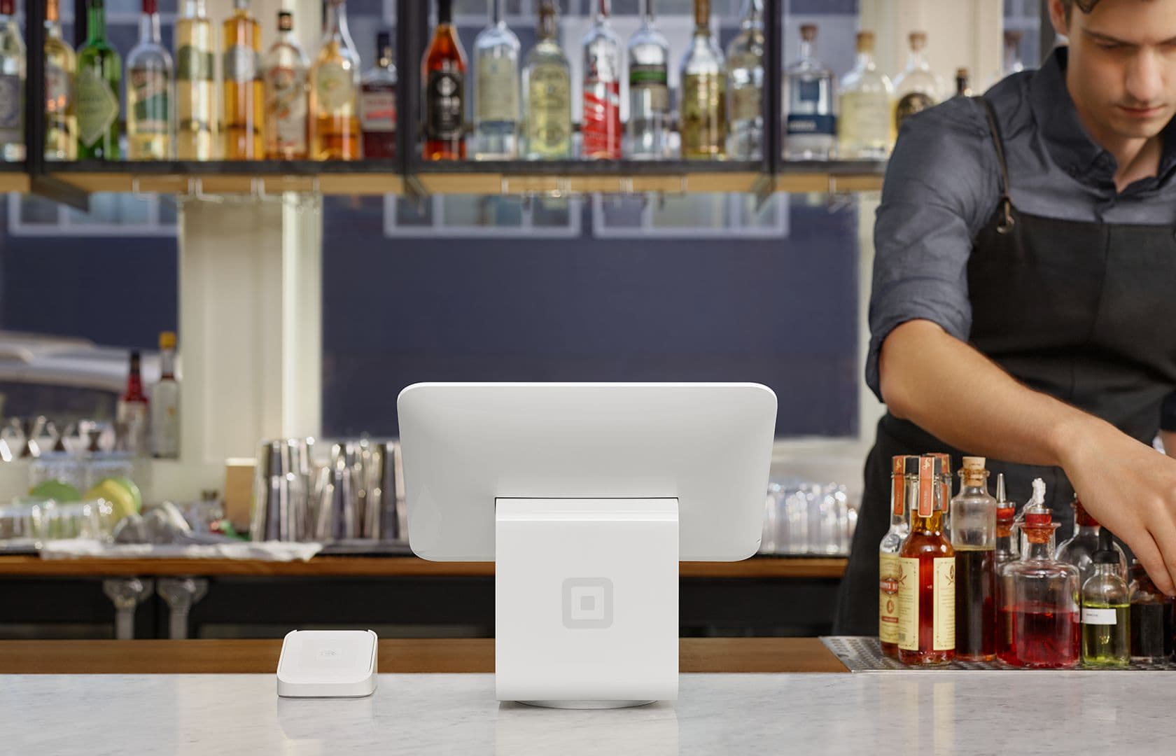 Bartender using digital register at bar counter.