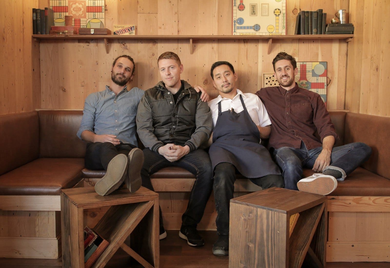 Four men sitting in a wooden room with games.