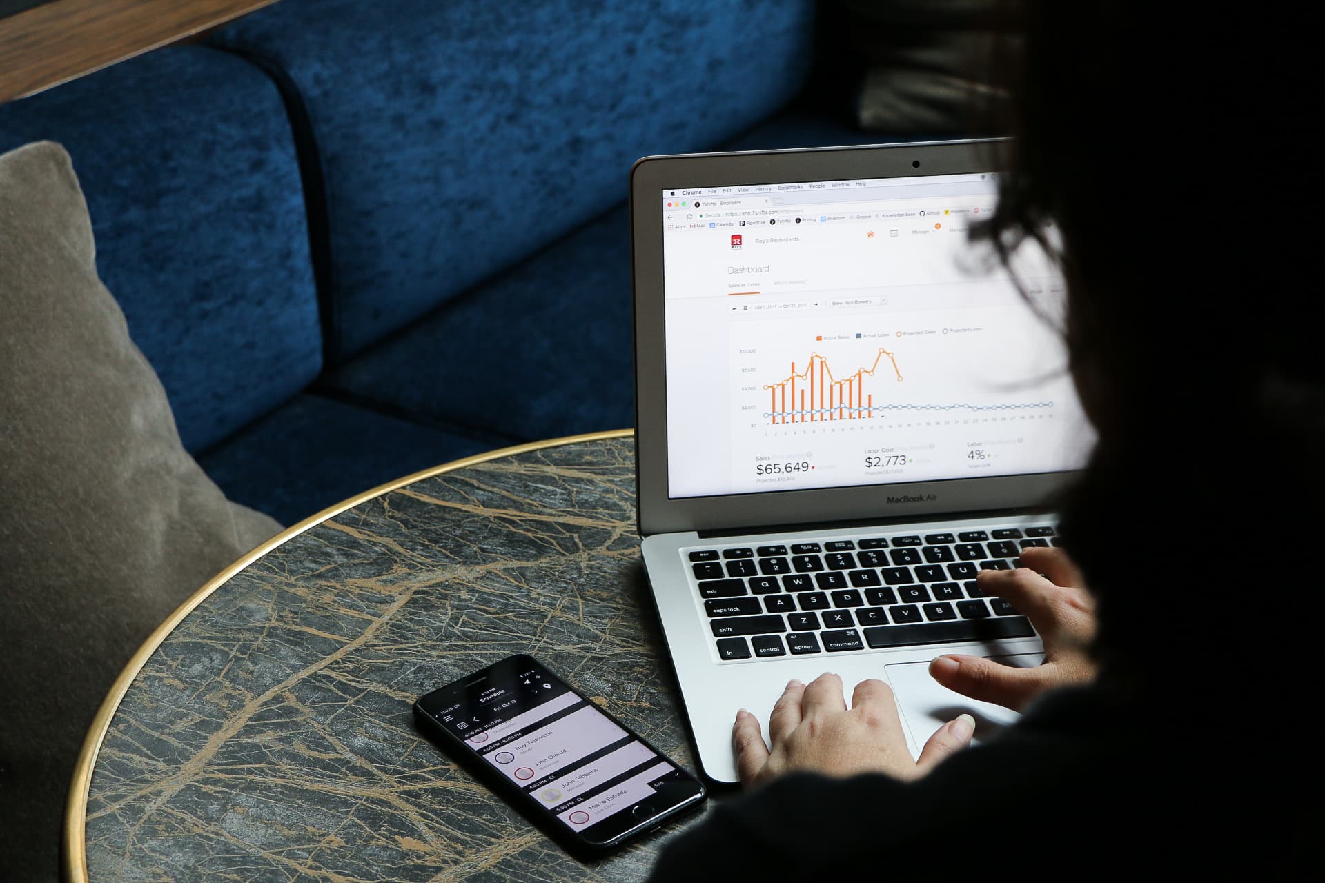 Person analyzing business data on laptop and phone.