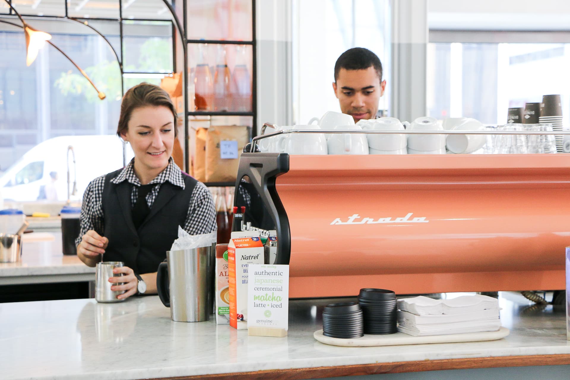 Baristas preparing coffee behind espresso machine