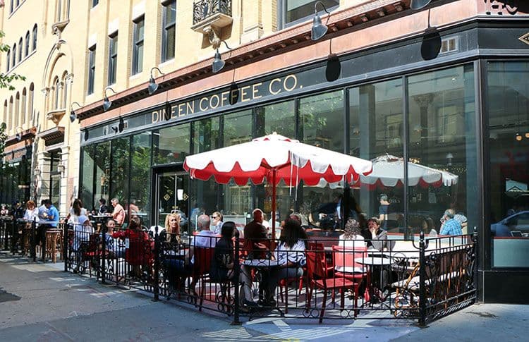 People enjoying coffee at sunny outdoor café.