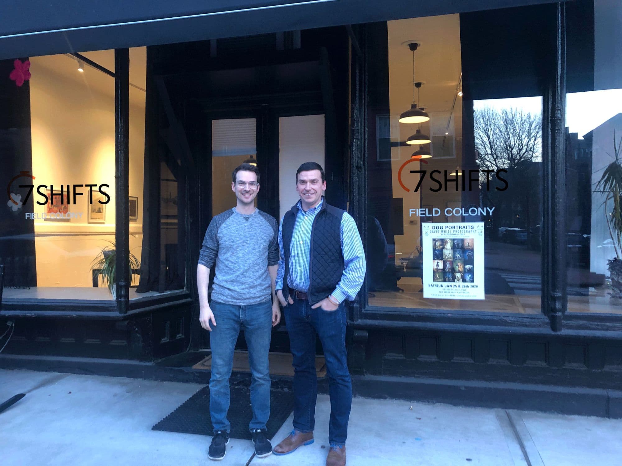 Two men outside 7 Shifts Field Colony building.