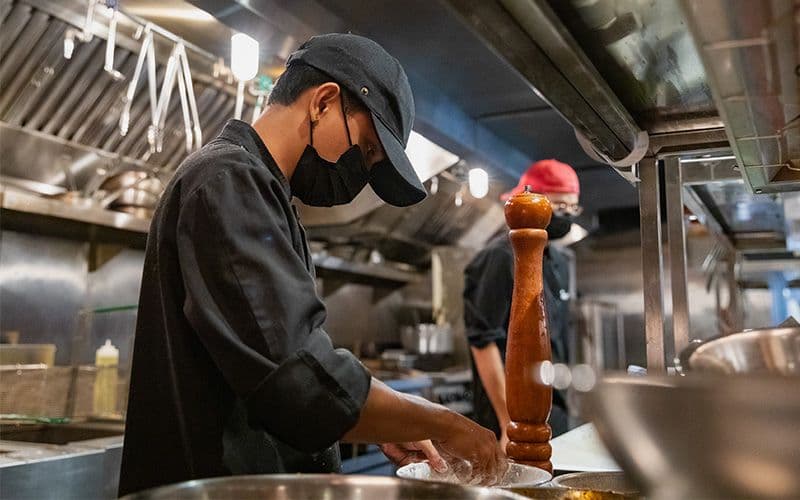 Chefs preparing dishes in a restaurant kitchen.