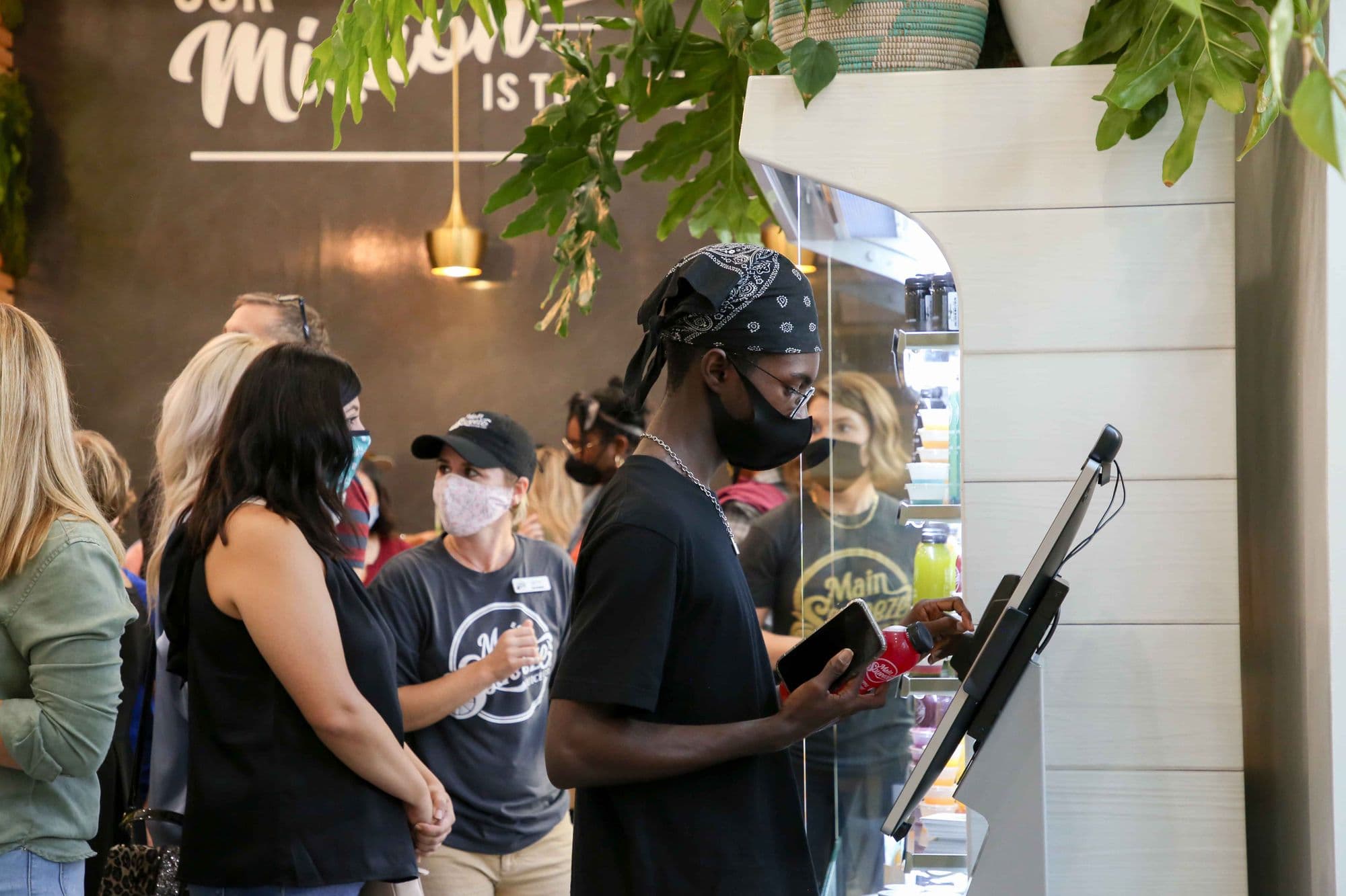 People ordering at a juice bar kiosk.