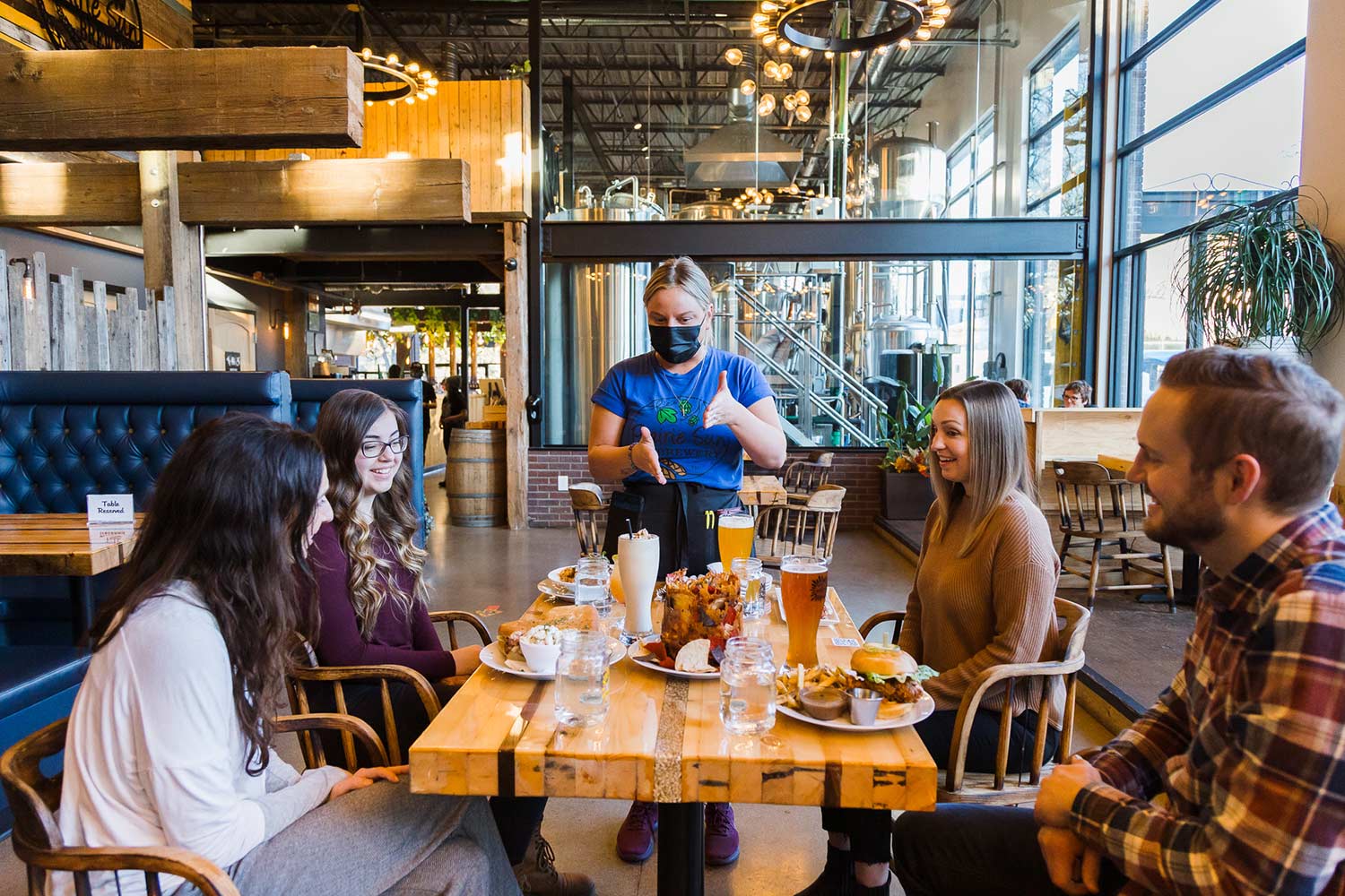 Group dining at rustic modern restaurant with server.
