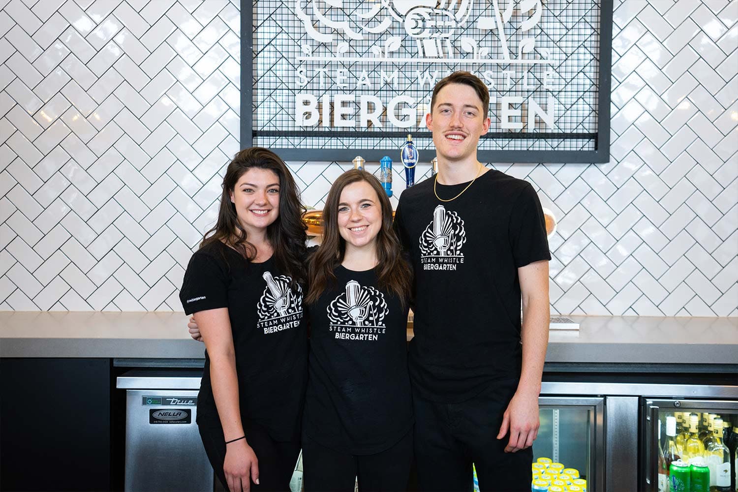 Three people smiling at Biergarten brewery.