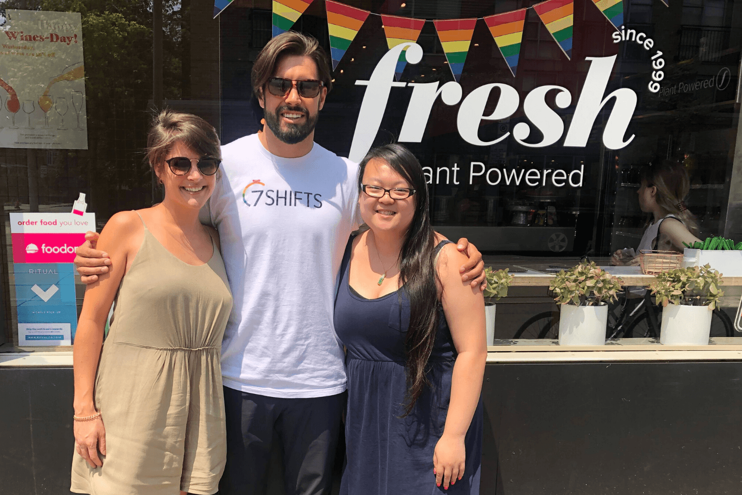 Three people smiling outside a plant-powered restaurant.