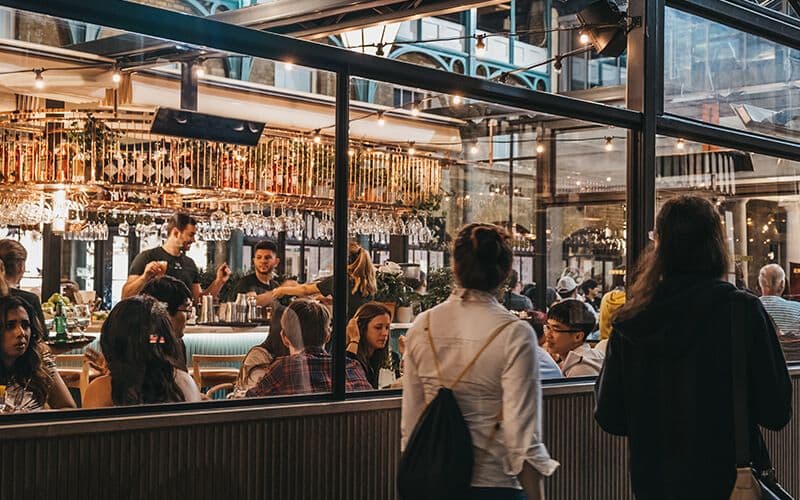 Busy indoor bar scene with patrons and bartenders.