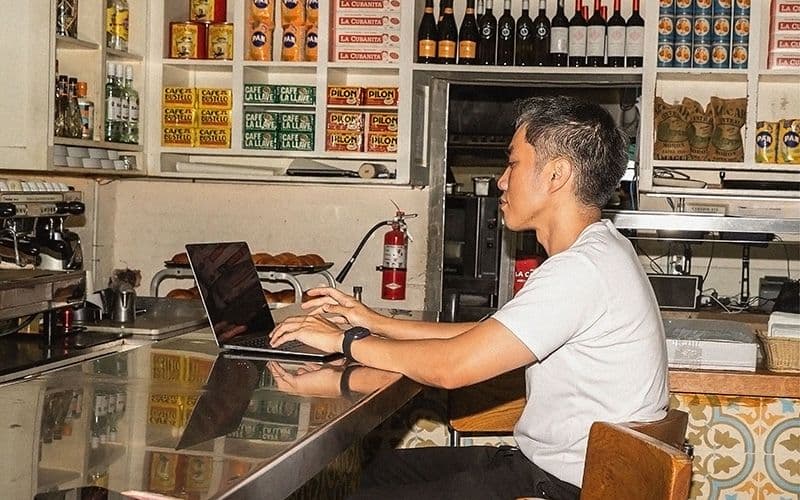 Man working on laptop at a cafe counter.