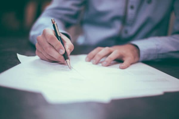 Person writing on documents with a pen