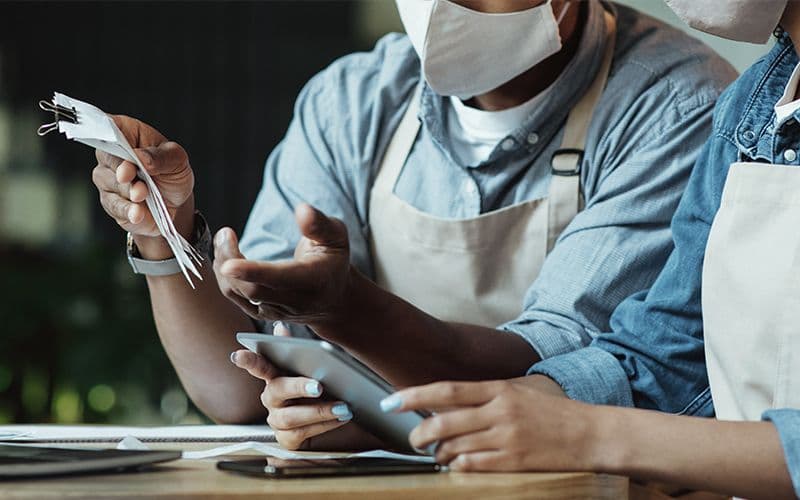 Masked workers discussing with tablet and papers