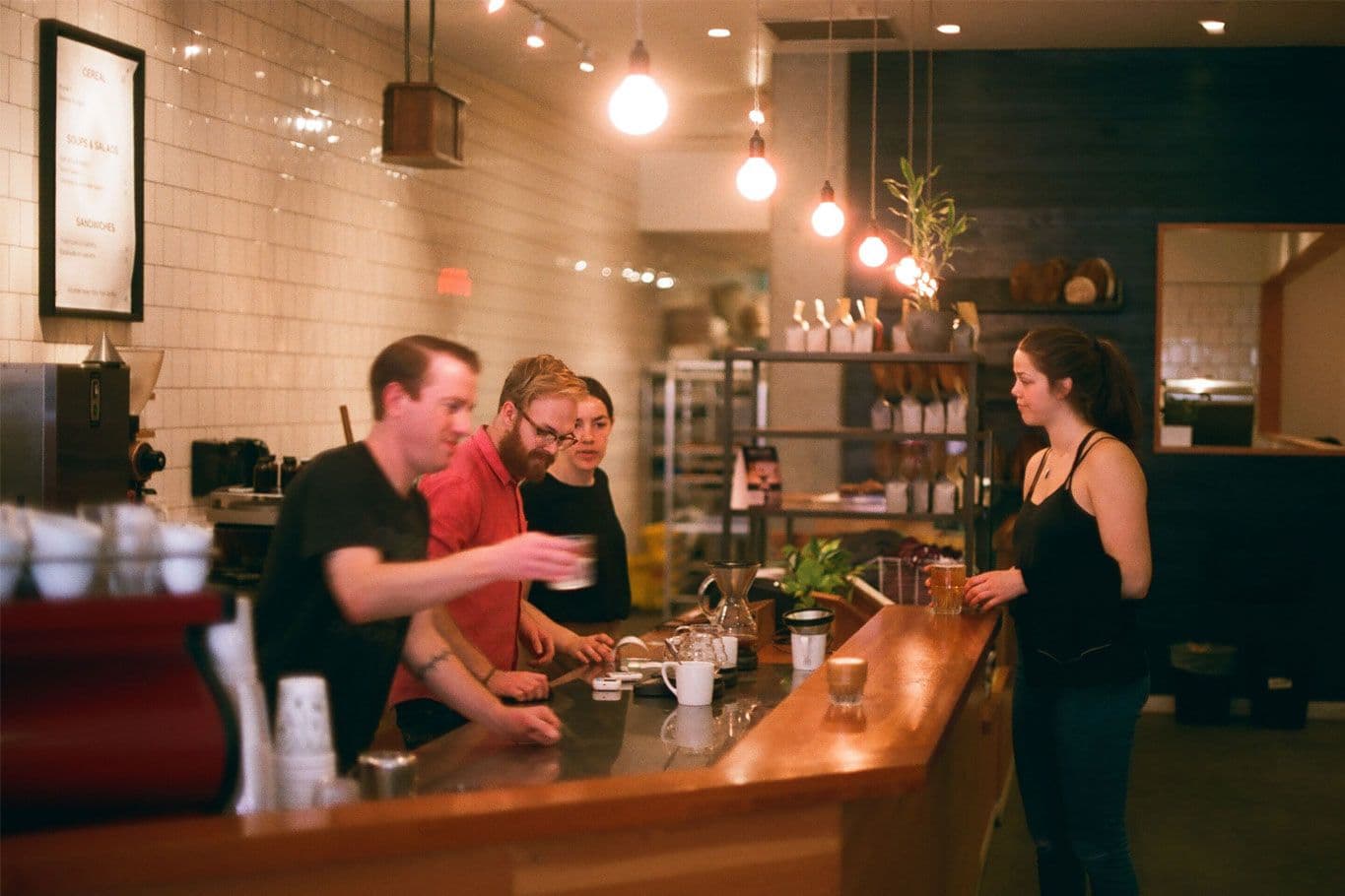 People socializing at cozy coffee shop counter.