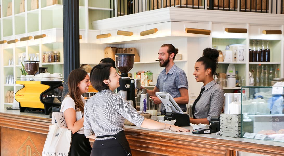 Customers and baristas chatting at coffee shop counter.