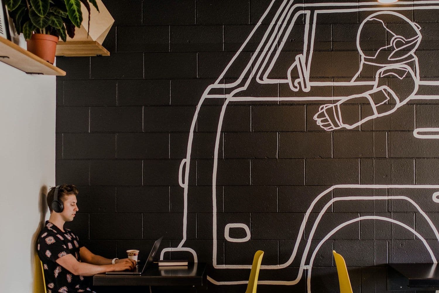 Person working on laptop near astronaut mural.