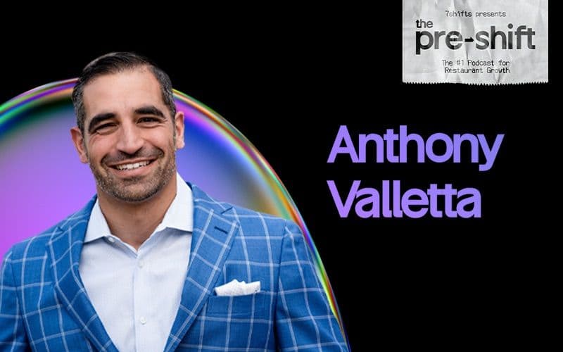 Podcast guest with rainbow background and suit jacket.