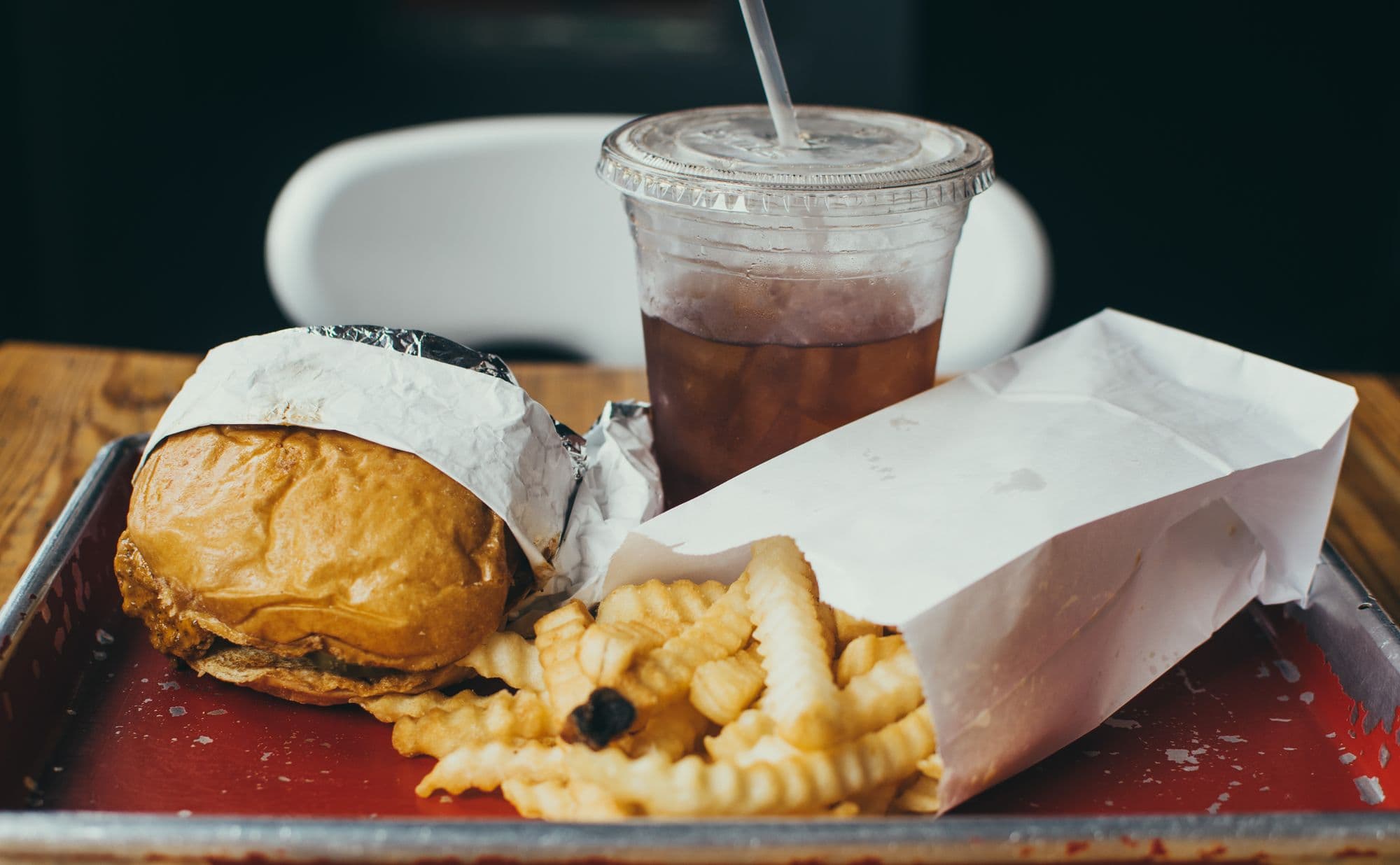 Burger, fries, and iced drink on a tray.