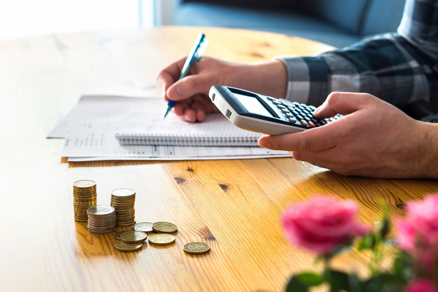 Person budgeting with calculator and coins on table.